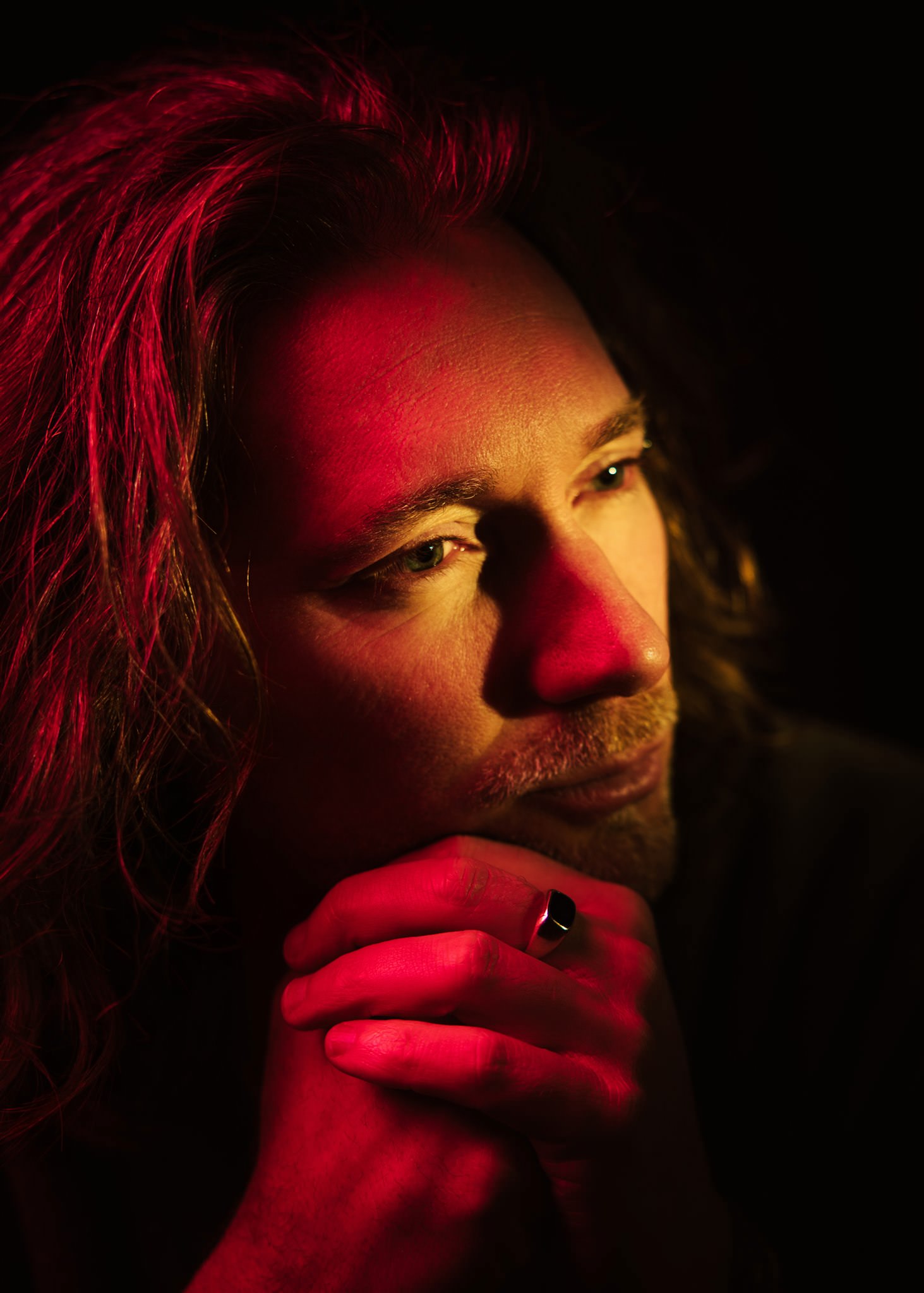 A moody warm toned portrait photo of melbourne musician Kris Mizzi